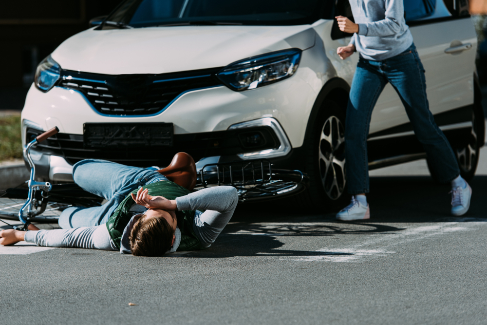 cropped shot of woman running to injured cyclist at traffic accident