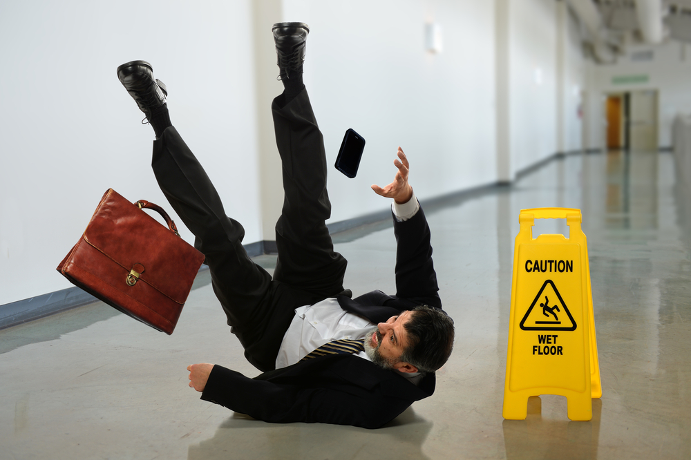 senior businessman falling near caution sign in hallway