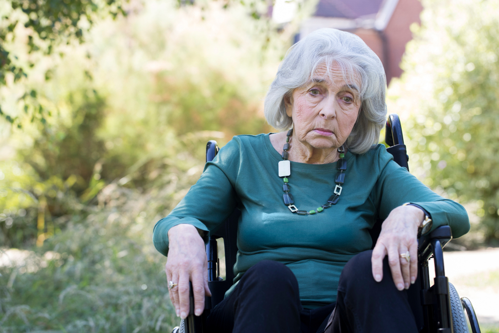 depressed senior woman in wheelchair sitting outdoors