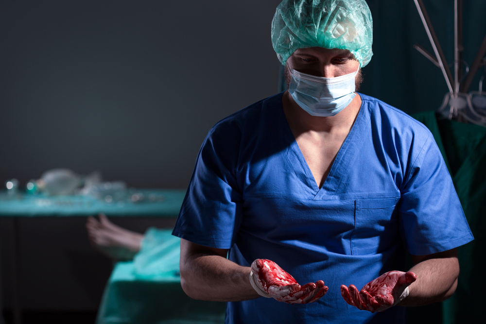 young surgeon with bloody hands after operation